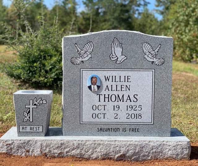 Standing headstone with vase and bird carvings. Photo